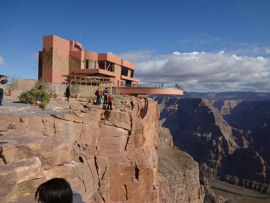 Esta figura es una imagen del mirador Skywalk del Gran Cañón. Es un edificio al borde del cañón con una pasarela que se extiende sobre este.