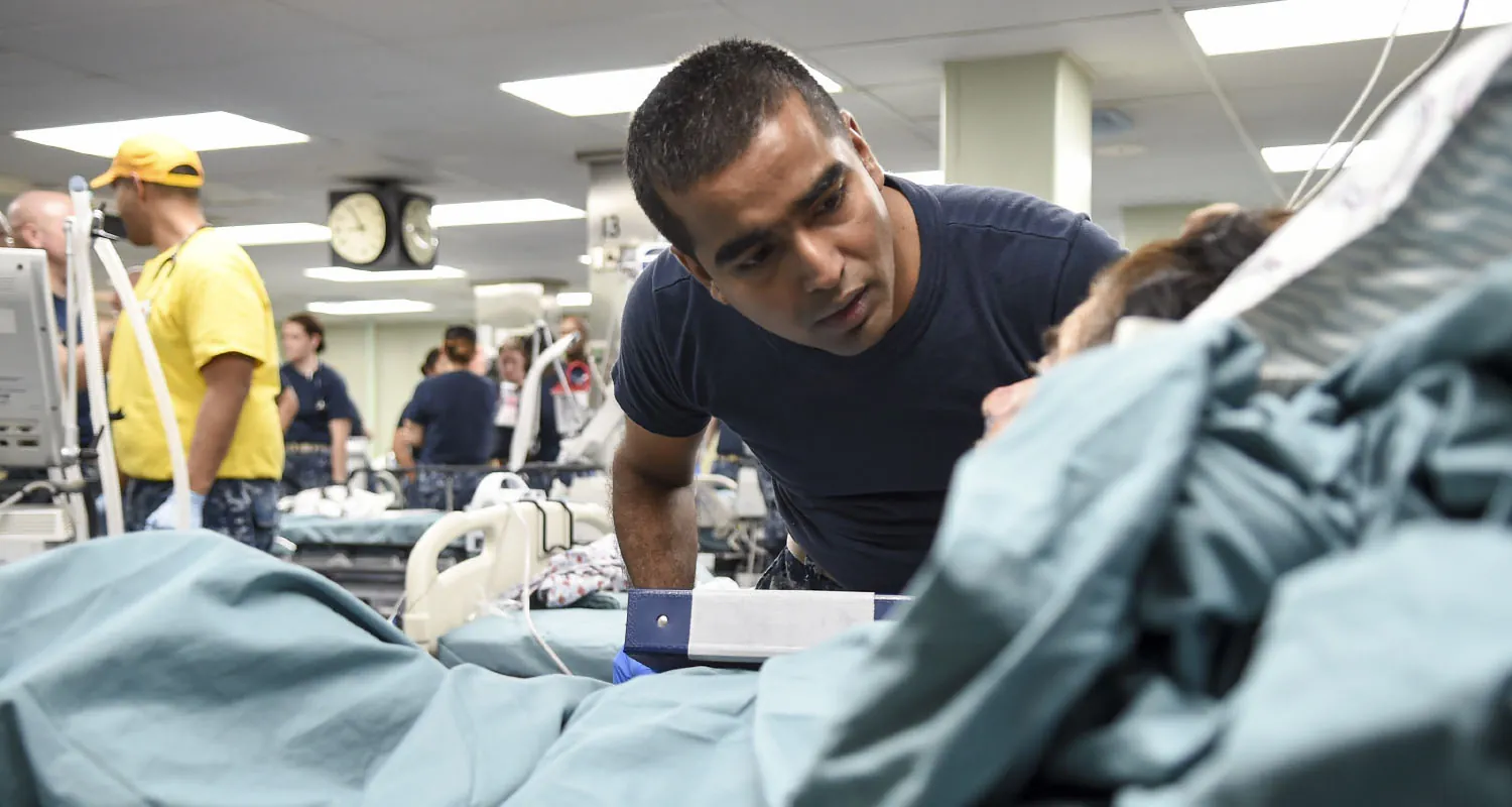 A nurse checking on a patient who is in bed.