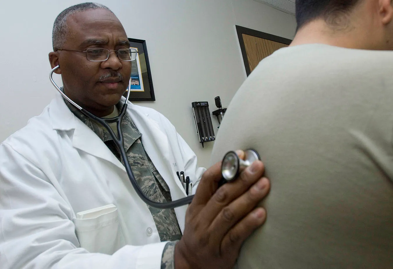 A doctor using a stethoscope on a patient’s back to assess breathing
