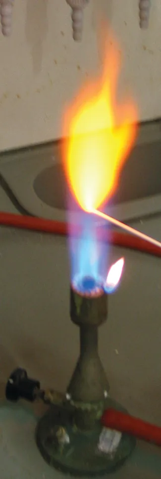 A photo of a lit Bunsen burner is shown. A wooden splint is placed in the flame, and a yellow flame is produced.