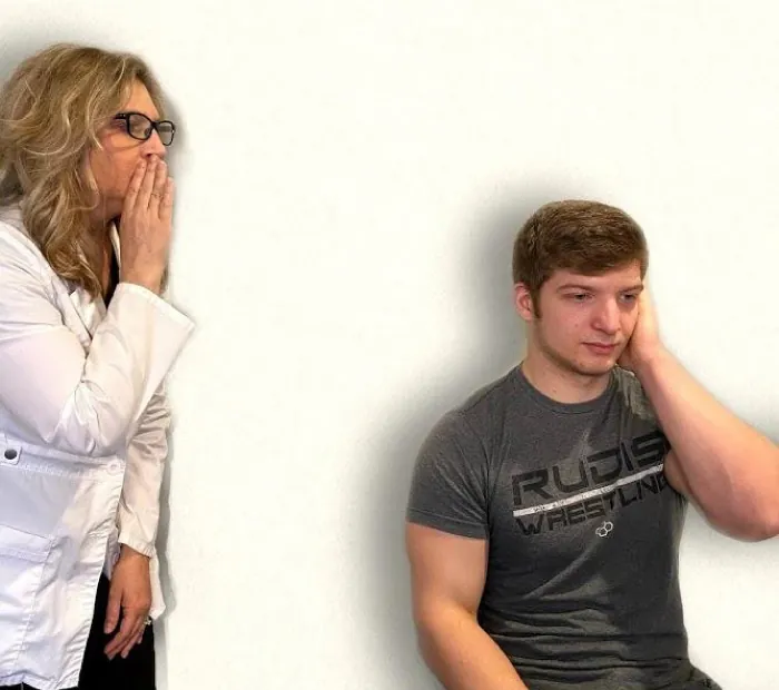 Photo showing a nurse whispering to simulated patient to assess hearing