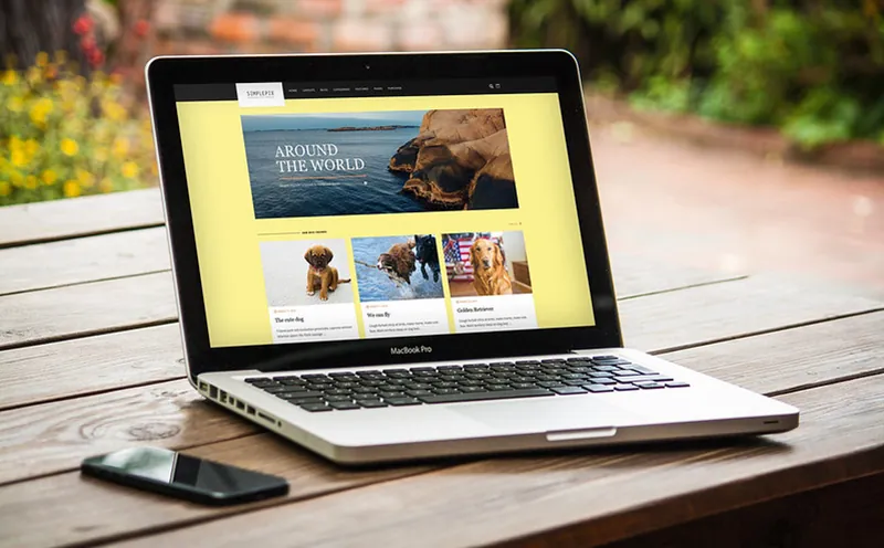 A laptop and a mobile phone appear on a table. The laptop display shows a webpage with a combination of words and images.