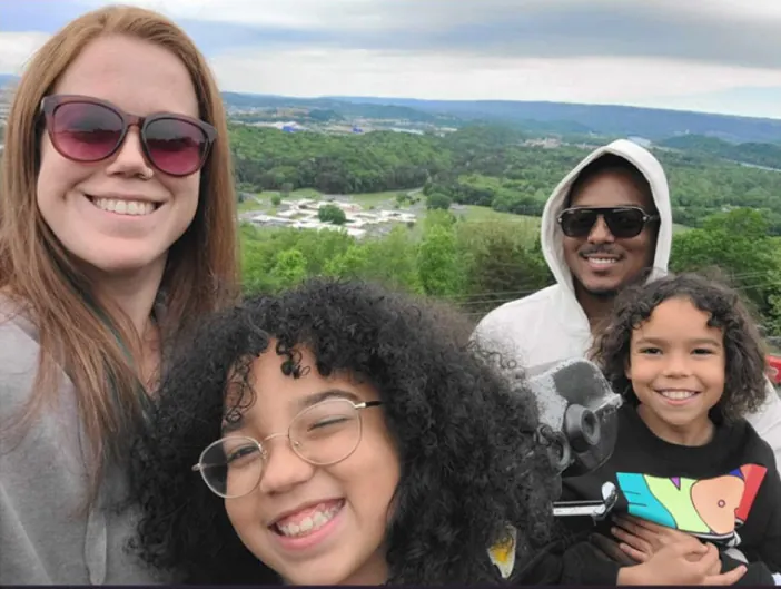 Photo of two adults and two children outdoors.