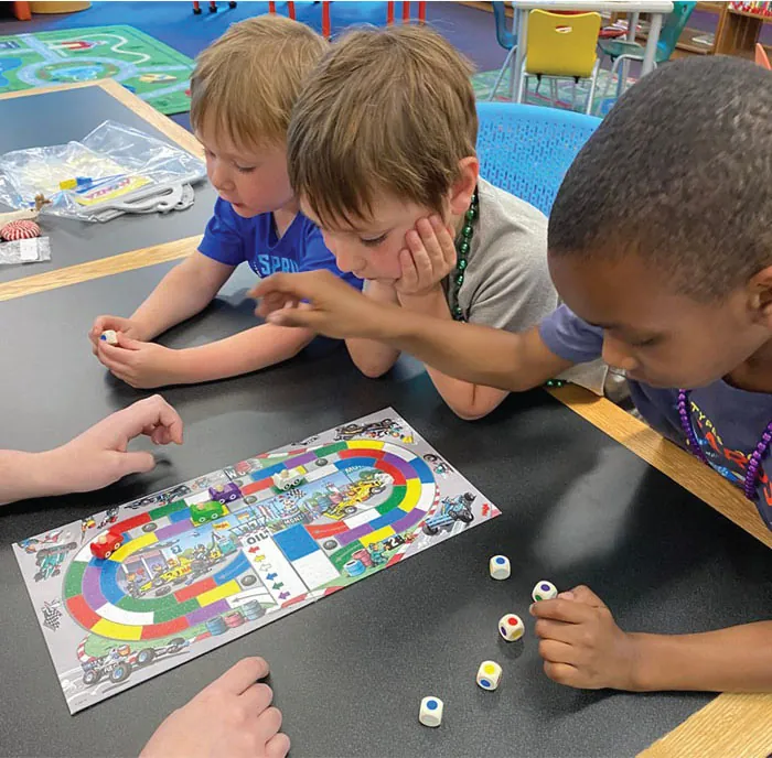 Photo of three children playing board games at a table.