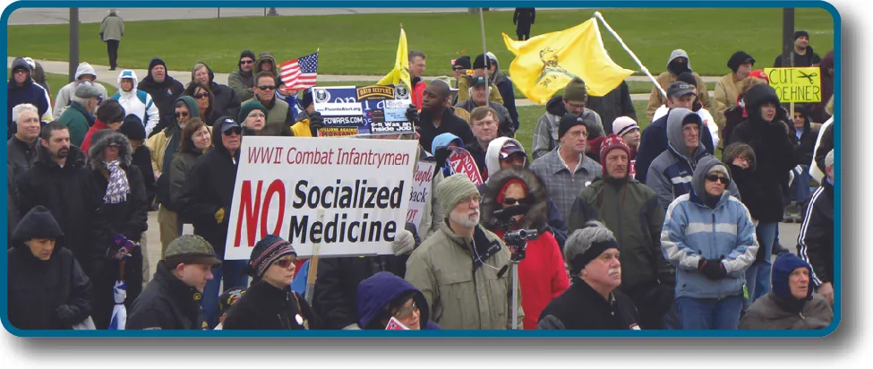 An image of a crowd of people holding signs and flags. One sign reads “WWII Combat Infantrymen No Socialized Medicine”.