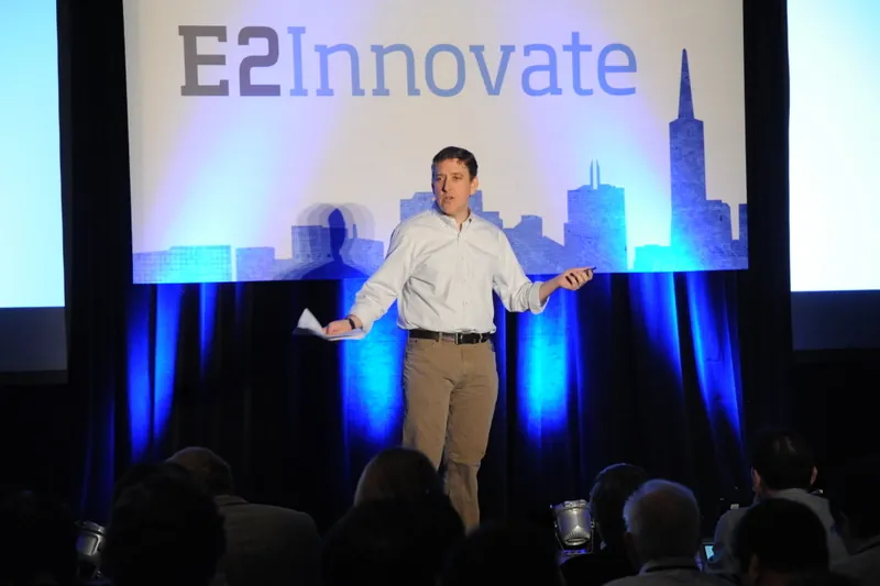 A photograph shows Ben Fried on stage, with a banner behind him that reads, E 2, innovate.