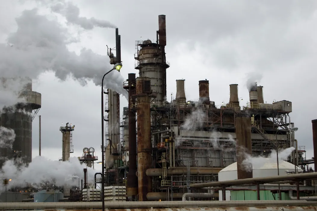A factory with multiple smokestacks emits smoke into the air.
