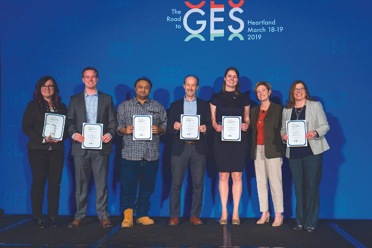A photo shows seven people holding up certificates after winning a pitch competition.