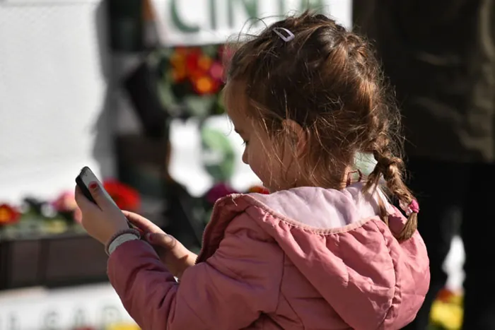 Photo of young child dialing a smartphone.