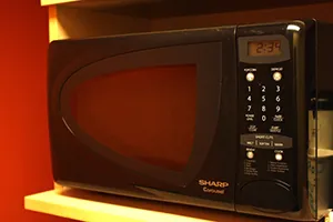 A small, counter-top microwave oven is shown. Microwave ovens use electromagnetic waves to heat food.