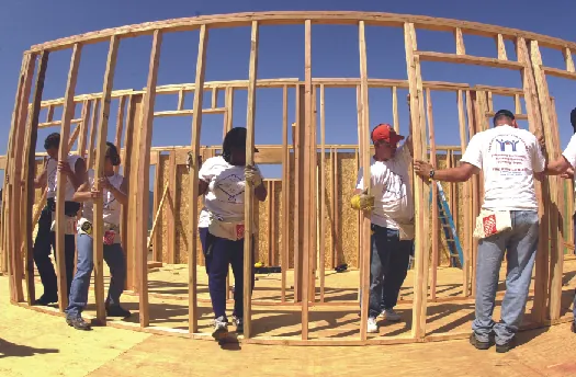 An image of several people working together to build the wooden framework of a building.
