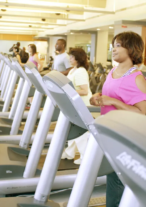 A row of people exercise on treadmills in a gym.