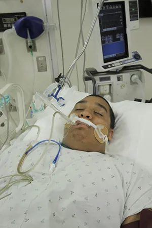 A photo of a person in a hospital bed with a mechanical ventilator.