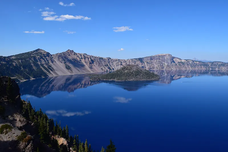 A large lake surrounded by rocky mountains, with a small island in the center.
