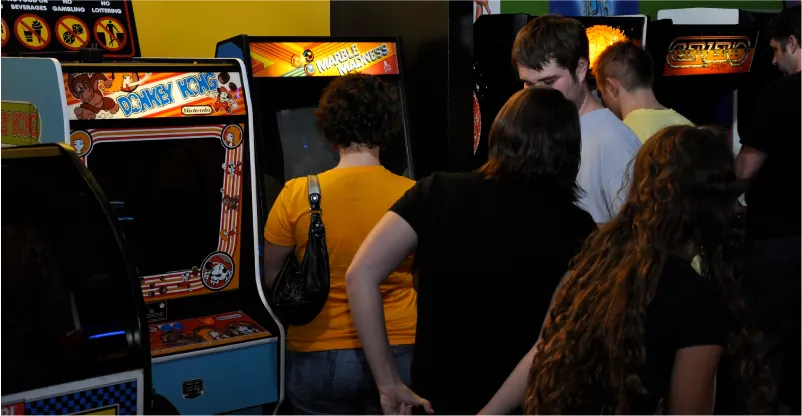 A group of people are standing in front of video arcade games.