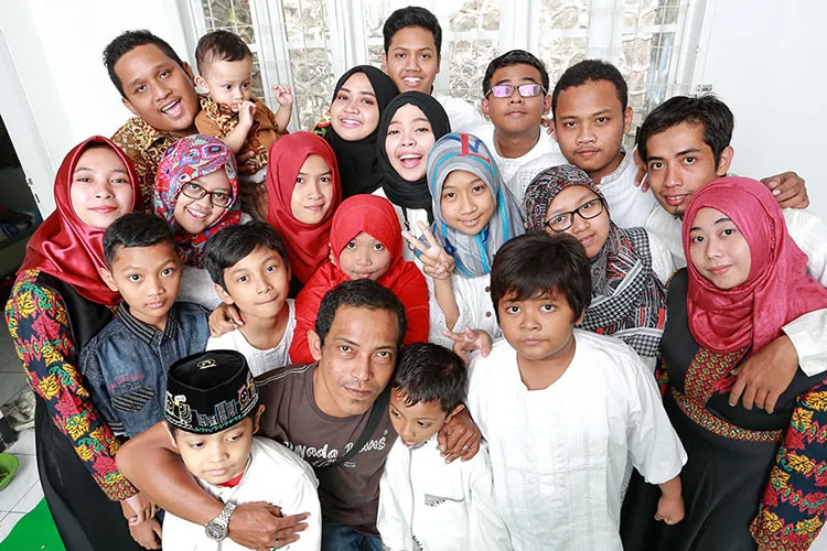 A group of men and women of varying ages are smiling and posing for a group photo.