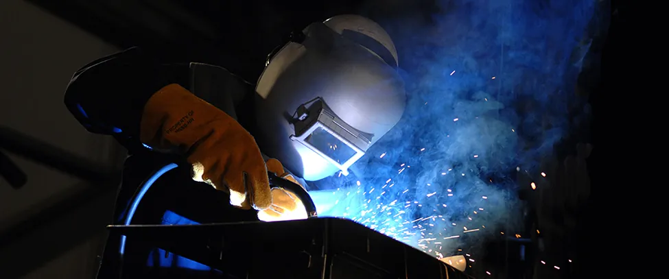 Sparks fly as a welder wearing a mask welds.