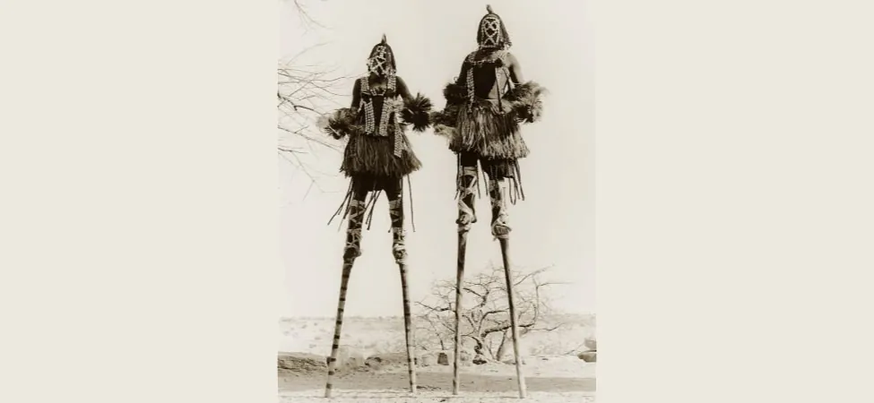 Picture shows a photograph of two stilt walkers in standing position.