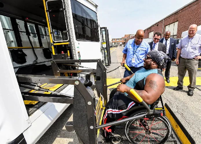 A person in a wheelchair uses a handicap lift to get on a bus.
