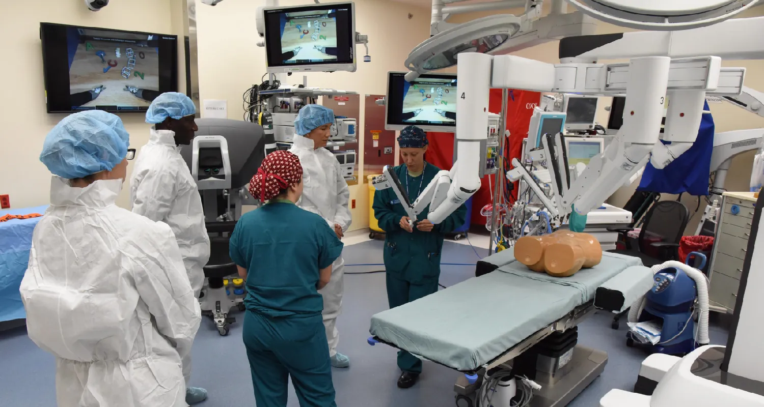 Photo of healthcare staff watching an individual demonstrate robotic equipment in a medical location.