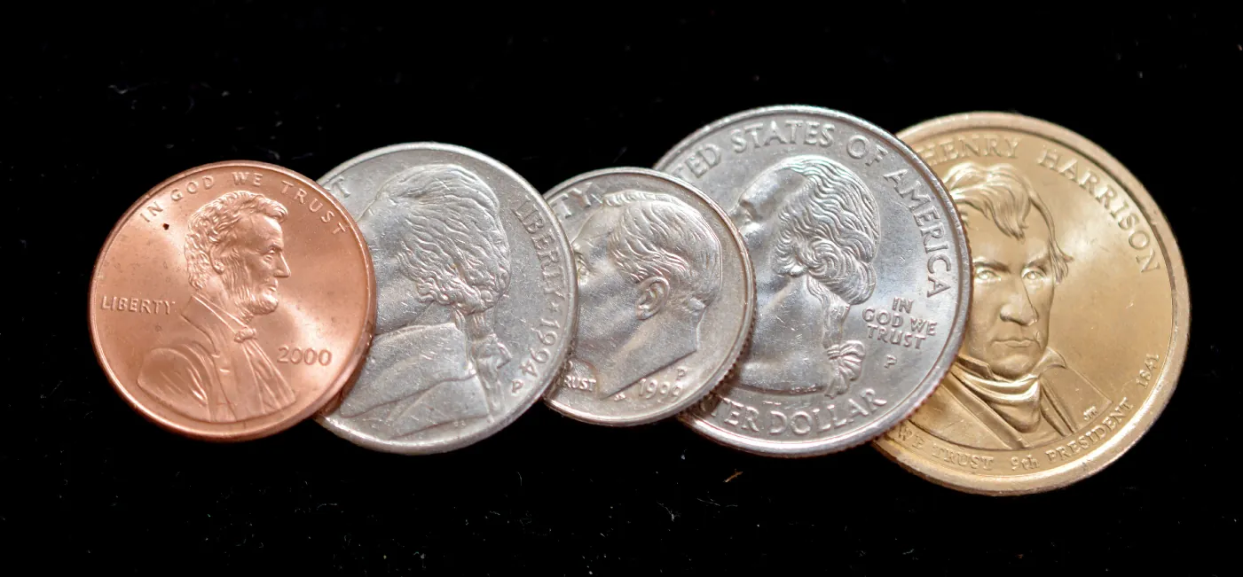 This is a photo of change a set of keys in a pile. There appear to be five pennies, three quarters, four dimes, and two nickels. The key ring has a bronze whale on it and holds eleven keys.