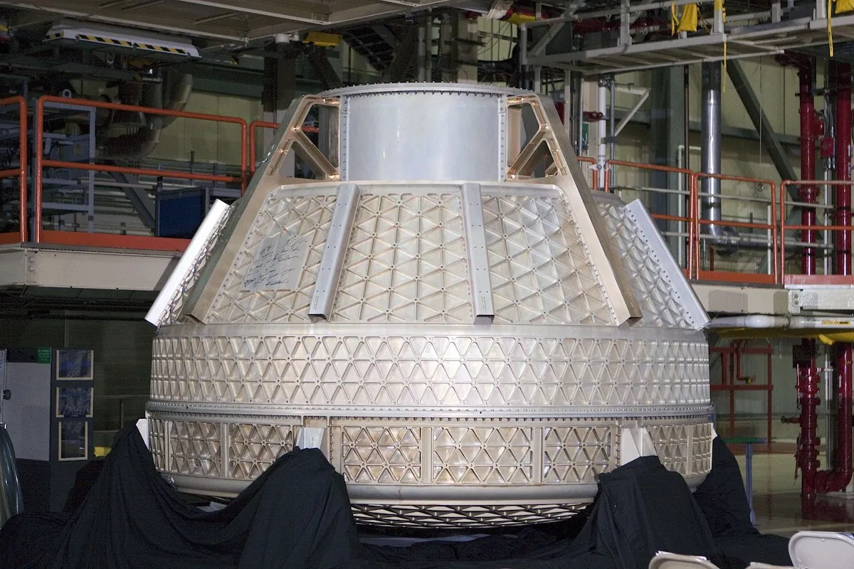 A large cylindrical vessel sits in a manufacturing facility. Visible on the outside are many triangular shapes protruding from the main surface.
