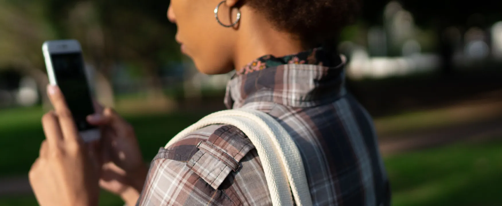 A close-up view of a person using smartphone outdoors.