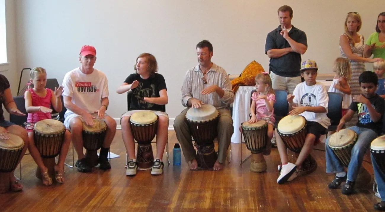 A photograph of people participating in a drumming circle.