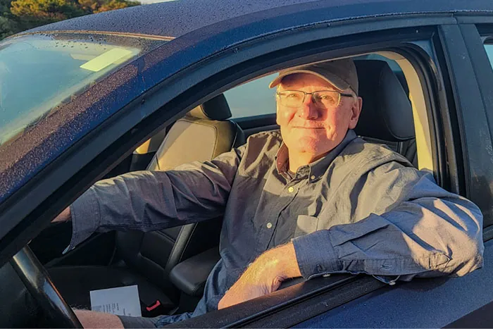 An older man is shown in the driver's seat of a car.