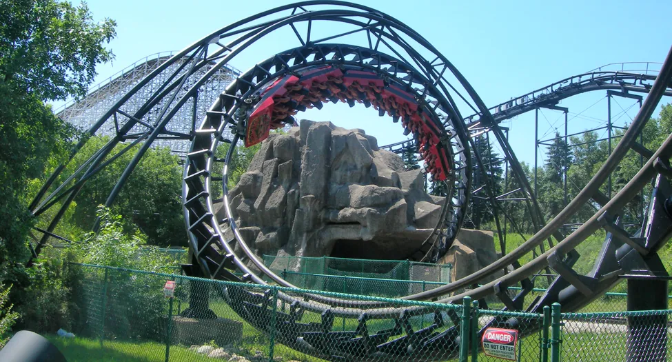 A photograph shows a roller coaster cart in an upside down position inside a roller coaster loop of a track