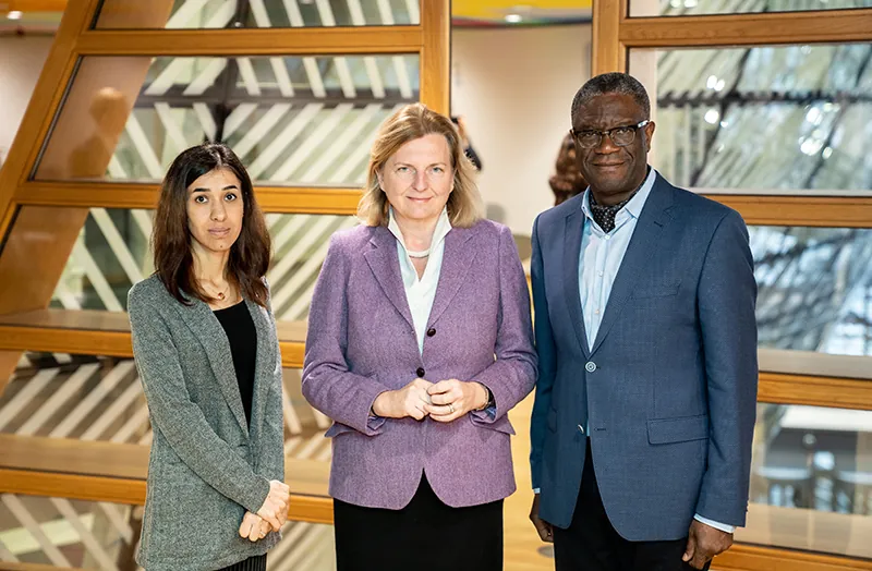 Three professionally dressed adults stand for a photograph.