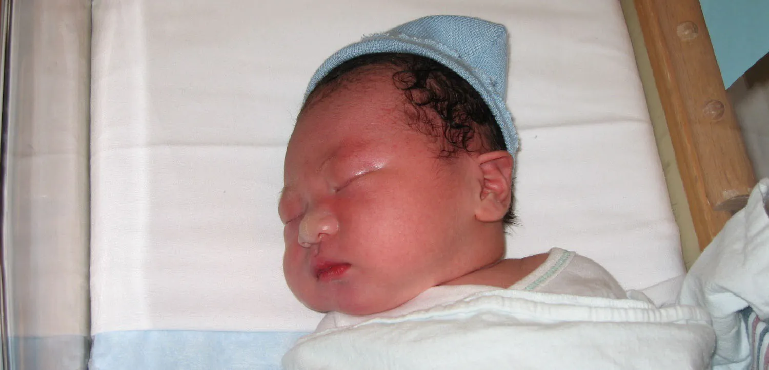 Photo of sleeping newborn in hospital bassinet.