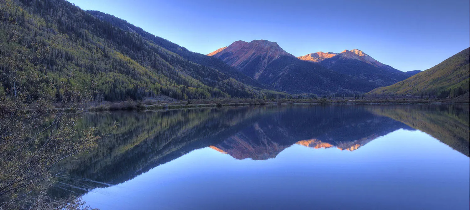The photo shows mountains and their mirror-image reflection in a lake.