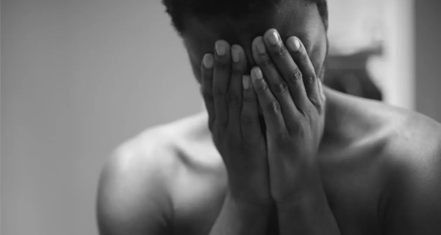 Photo of person with their hands over their face.