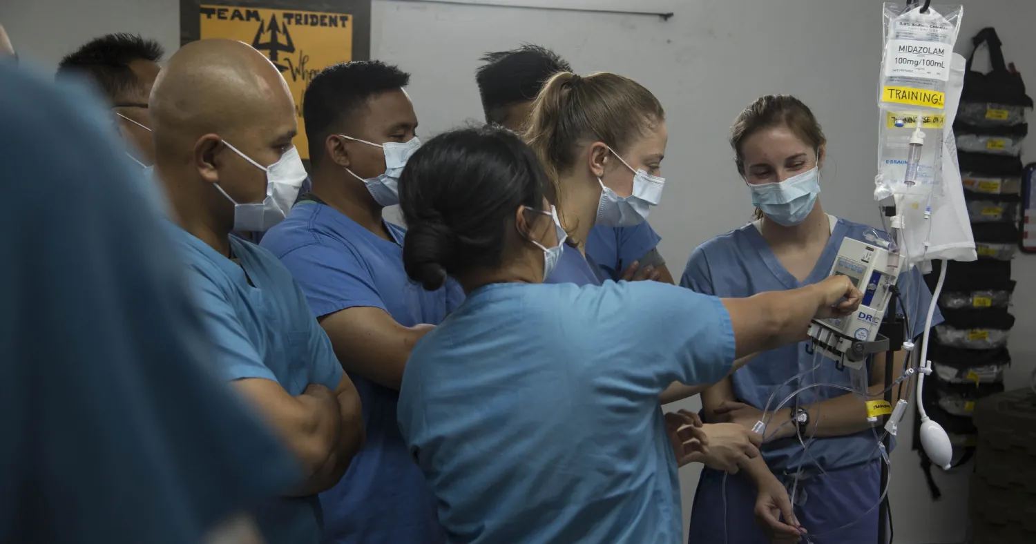 Photo of an intensive care unit nurse conducting training with other nurses on intravenous drip medications.