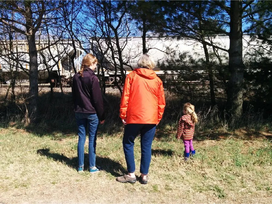 Photo of a grandparent, parent, and child outside.