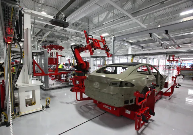 Photo of glass roof installation on a car in a factory using machinery.