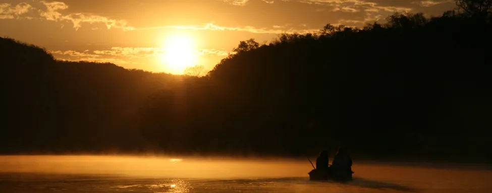 A photo of a boat on a lake at sunset.