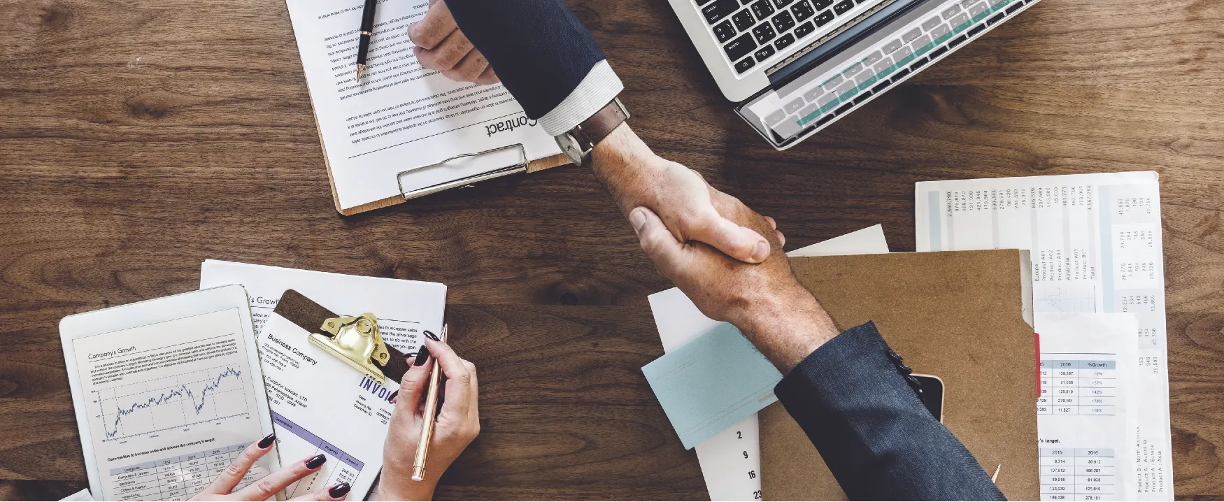 Two hands shaking over a wooden surface.