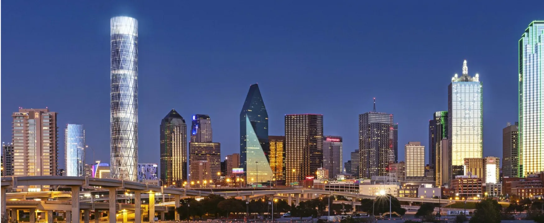 A photograph shows a brightly lit city skyline. Many of the buildings appear to be newly constructed and made entirely of glass.