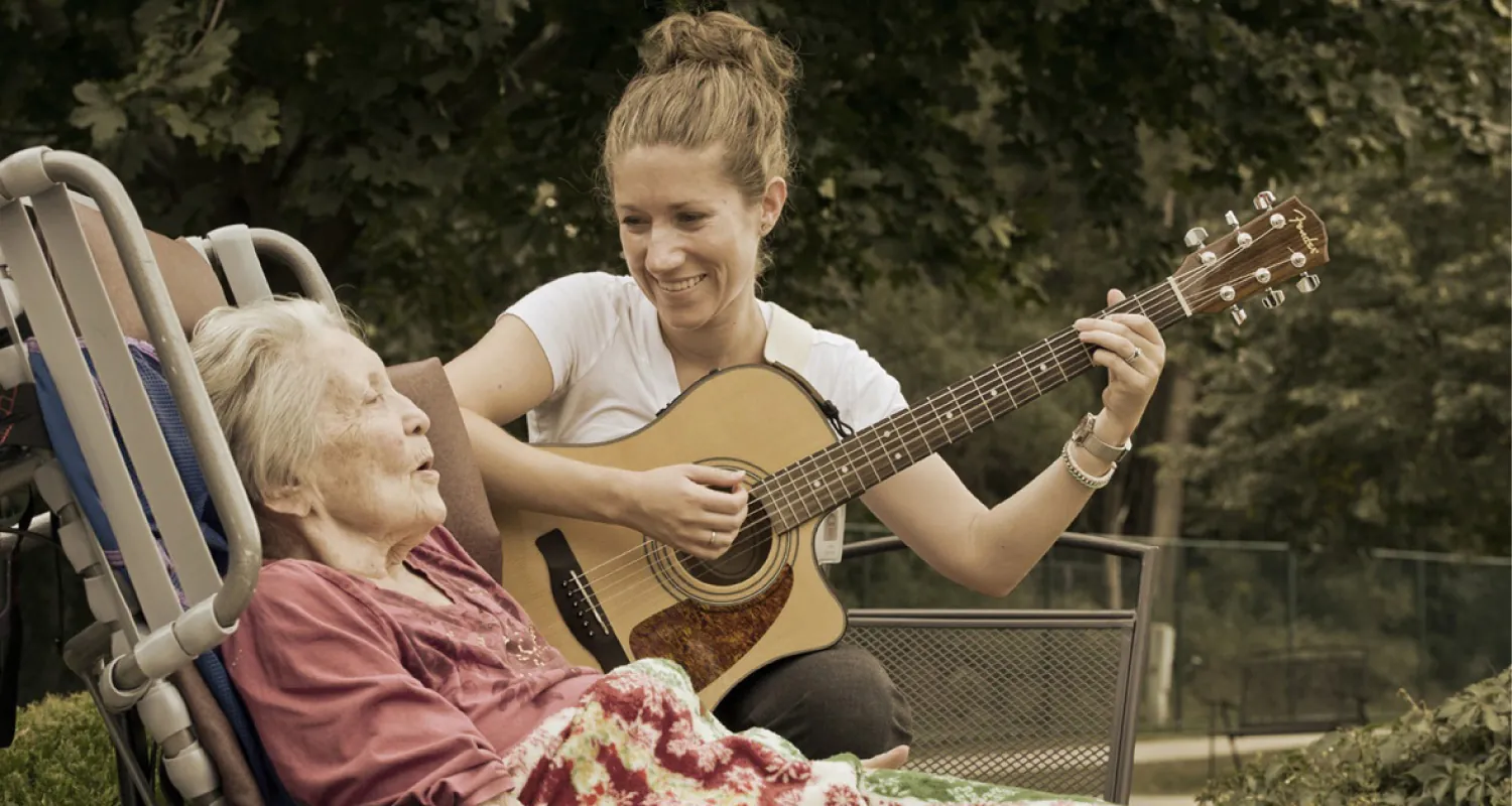 Peoria, IL - U.S. Air Force Staff Sgt. Carrie Gatz, an instrumentalist with the 566th Air Force Band, Illinois Air National Guard, plays guitar for a hospice patient at her civilian job Sept. 11, 2013. Gatz has served in the Air National Guard since 2004.