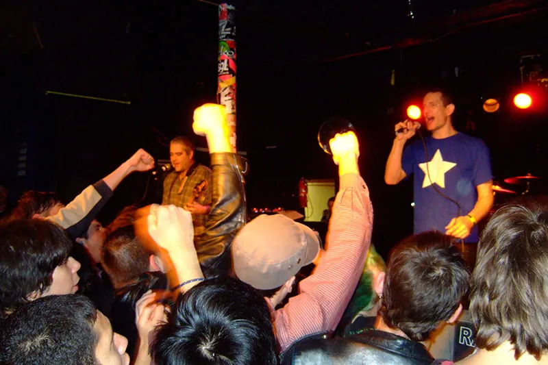 Naked Raygun, an American punk band, performs at Riot Fest, Chicago, 2012. A group of spectators cheers for them.