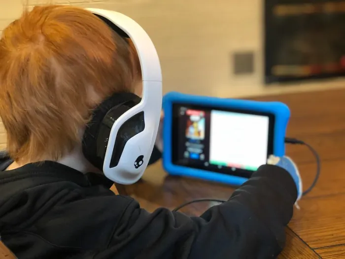 Photo of toddler wearing headphones and watching an iPad.