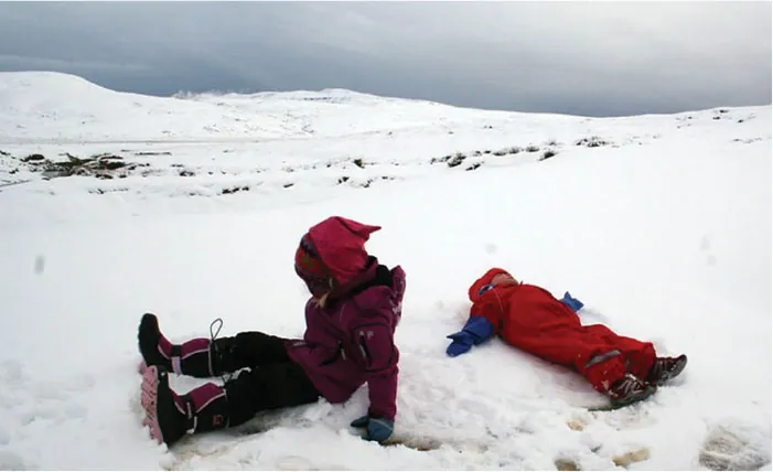 Image of two children dressed in snowsuits making snow angels in the snow.
