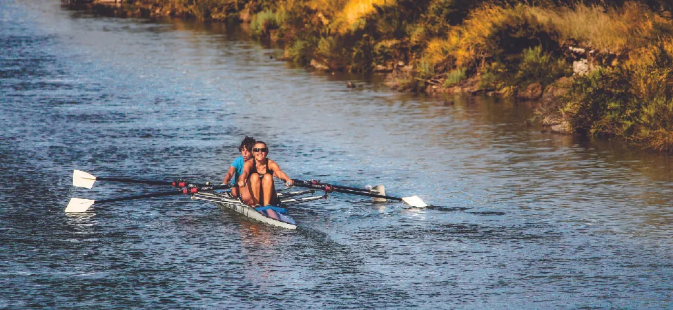 This is a photo of two people rowing a boat in a canal.