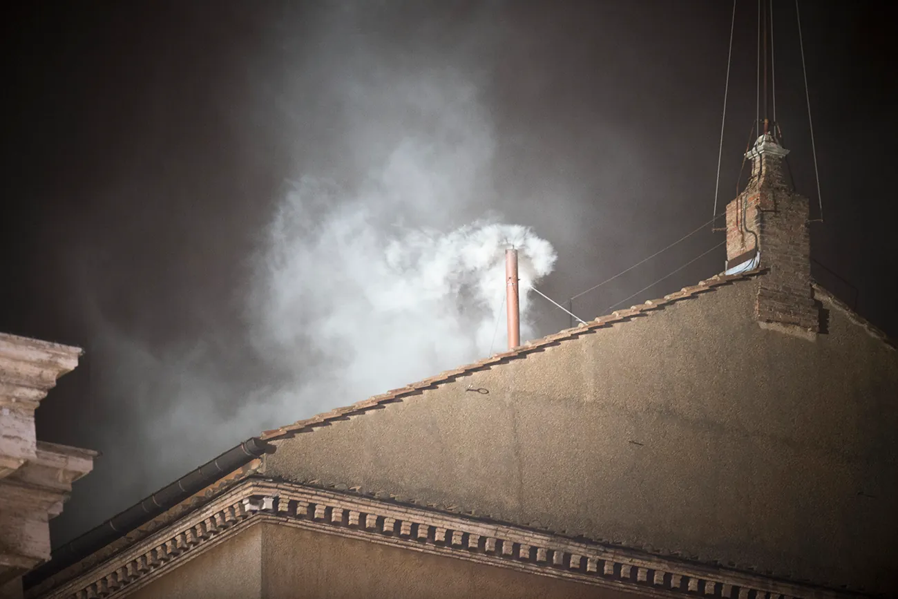 A photo shows white smoke rising from the chimney of the Sistine Chapel in Vatican City.
