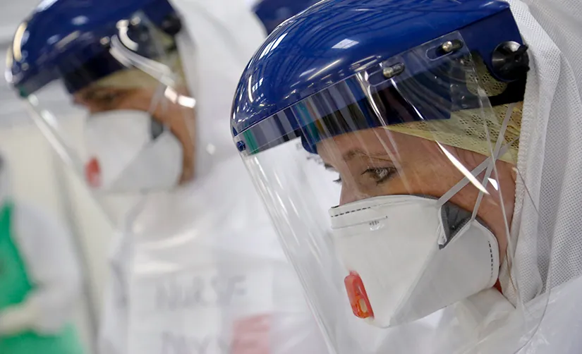 This photo depicts medical workers with a face mask and gloves training for safety so they can enter infection zones.