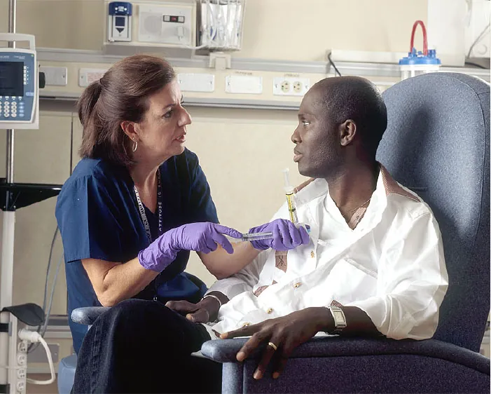 Photo of healthcare worker talking with individual sitting in a chair while administering a treatment.