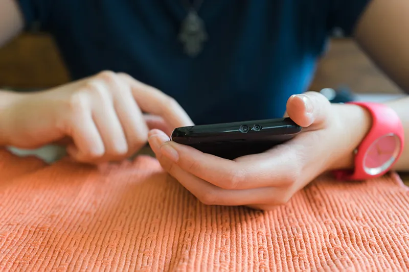 A close up photo shows two hands holding a smartphone.