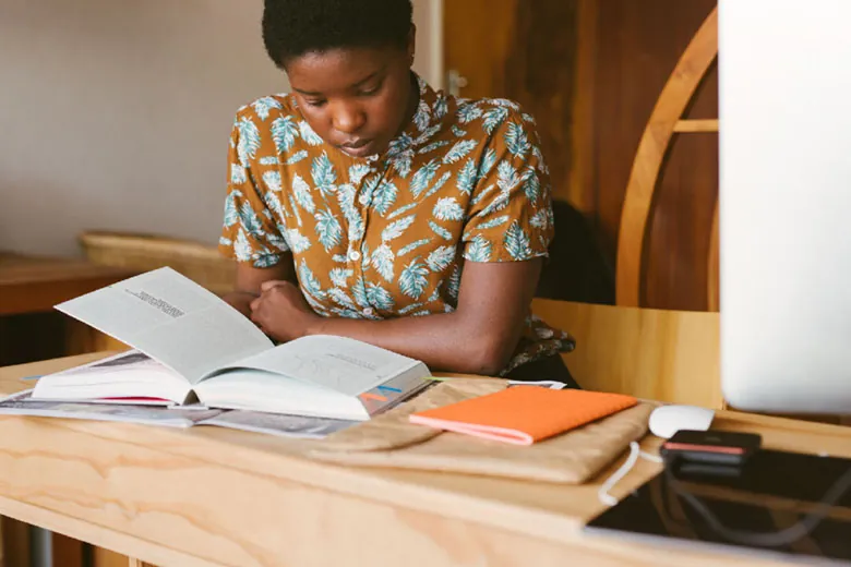 A student sitting at a desk and studying from a textbook.